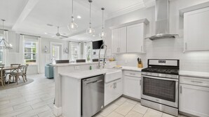 A modern kitchen with white cabinetry, stainless steel appliances, and pendant lighting. - Prime Location Near Community Pool | 6 Beach Bikes | Tram to Easy Beach Access (Santa Rosa Beach)