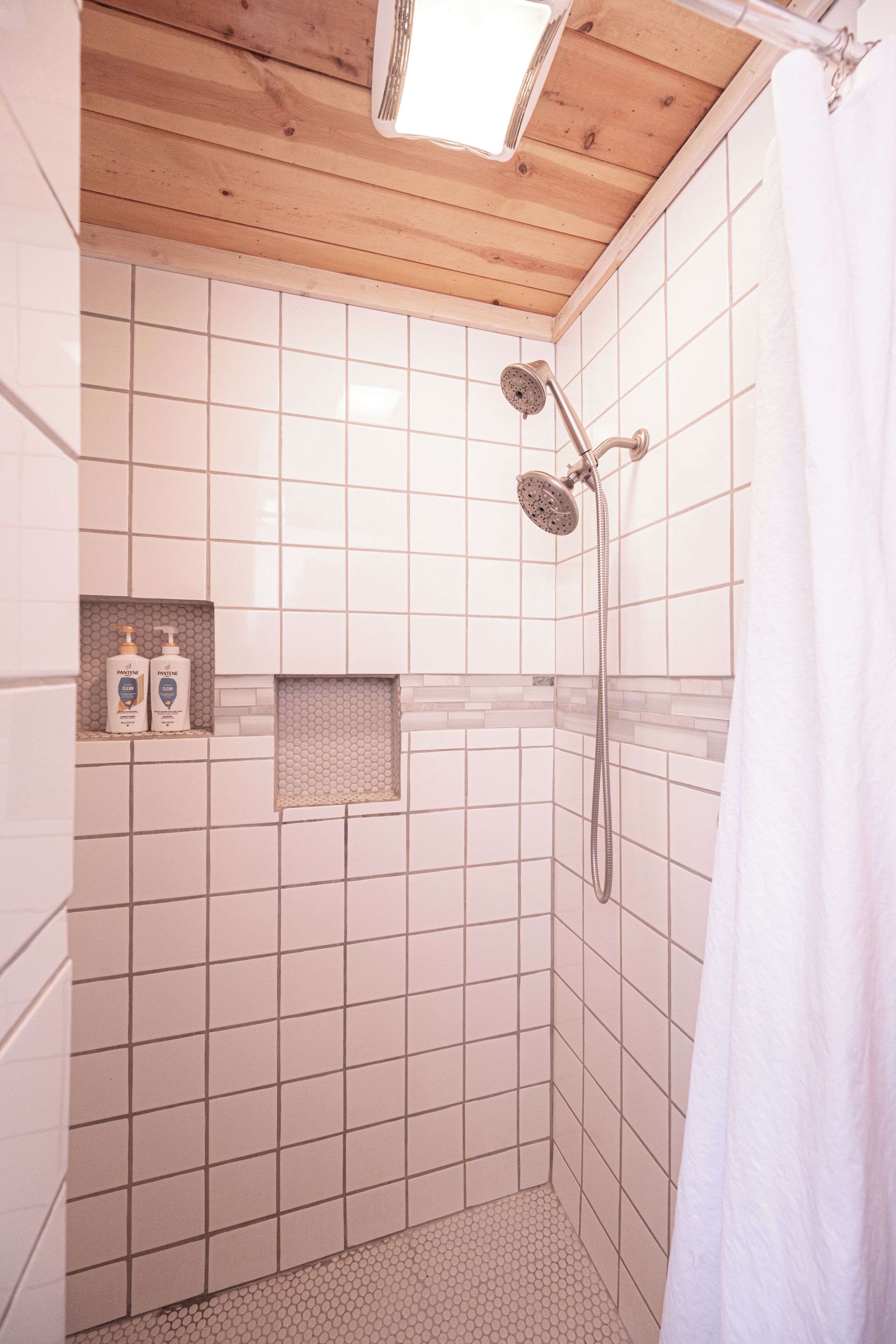 Ducha con cabezal de ducha de mano, barra para toallas y un estante pequeño con artículos de aseo.