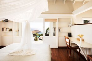 Relax in this serene bedroom with a large bed and a desk near a window offering a view of the outdoors.