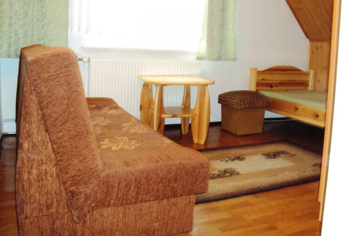 A small, cozy room with a sofa, a small wooden table, and a bunk bed.