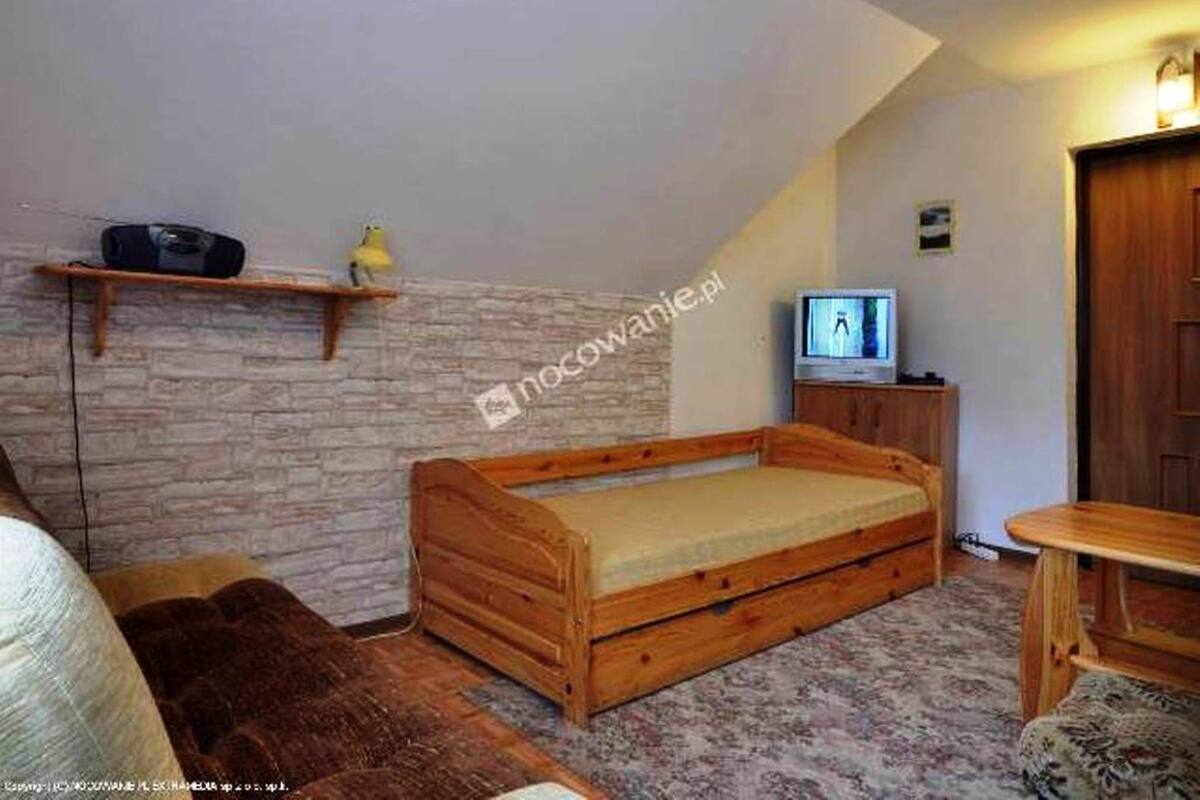 A cozy room with a wooden bed, a television, and a small shelf with a bird figurine.