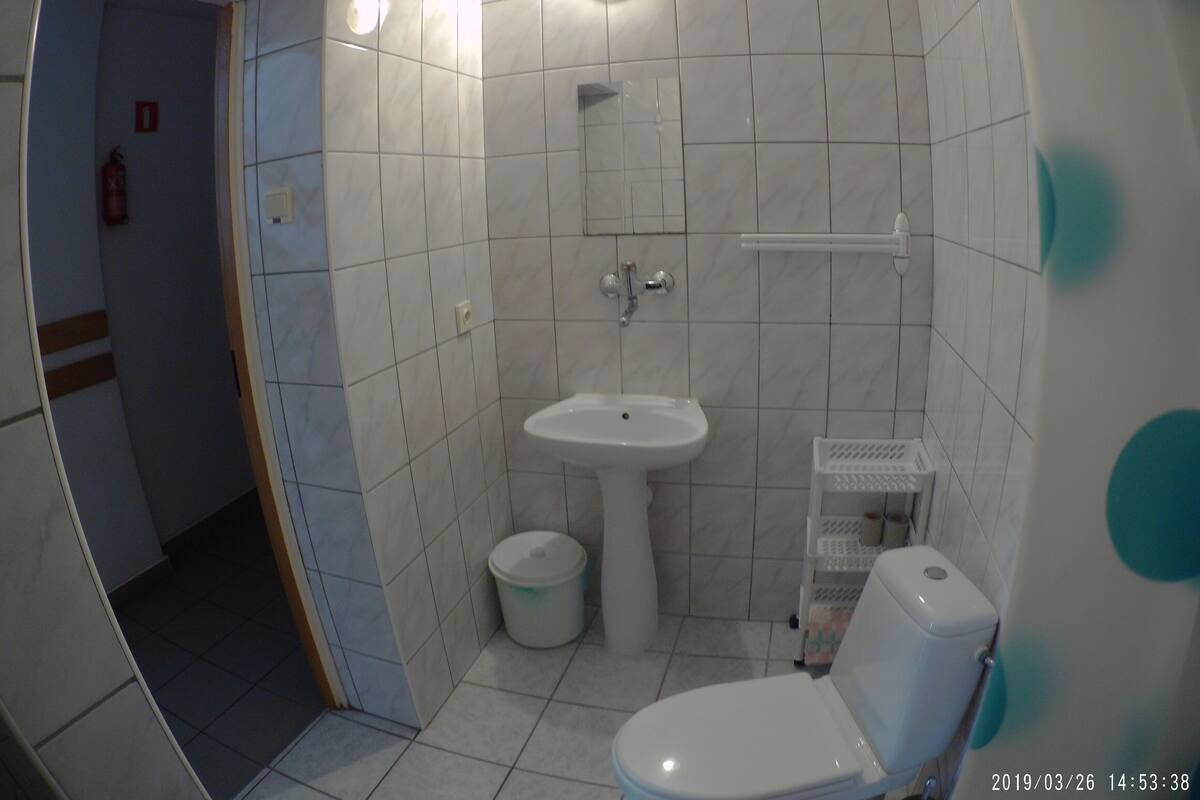 A small bathroom with a toilet, sink, and a small trash bin.