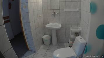 A small bathroom with a toilet, sink, and a small trash bin.