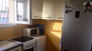 Een kleine keuken met een magnetron, fornuis en koelkast.