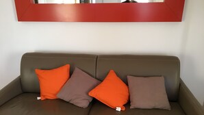 Een bruine leren bank met vier kussens in oranje en bruin.