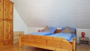 Un lit en bois dans une pièce dotée d’un plafond en pente et d’une armoire.