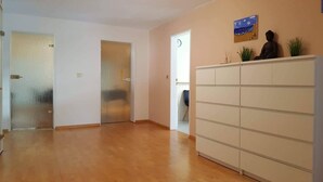 Un couloir doté d’un plancher en bois, d’une armoire blanche et d’une porte en verre dépoli.