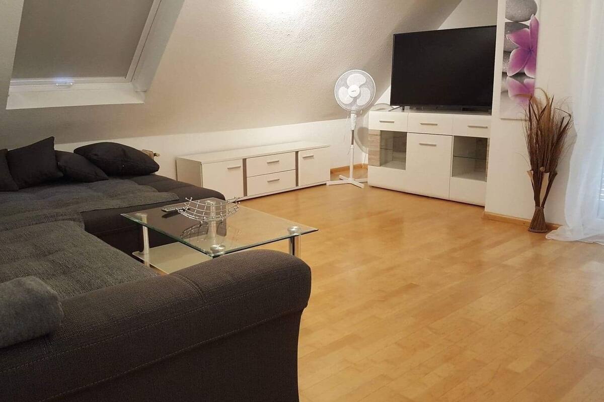 Una sala moderna con un sofá modular, una mesa de centro de vidrio, un televisor de pantalla plana y un armario blanco.
