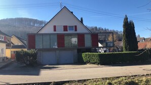 Un bâtiment à deux étages avec une façade rouge et blanche, de grandes fenêtres et un garage.