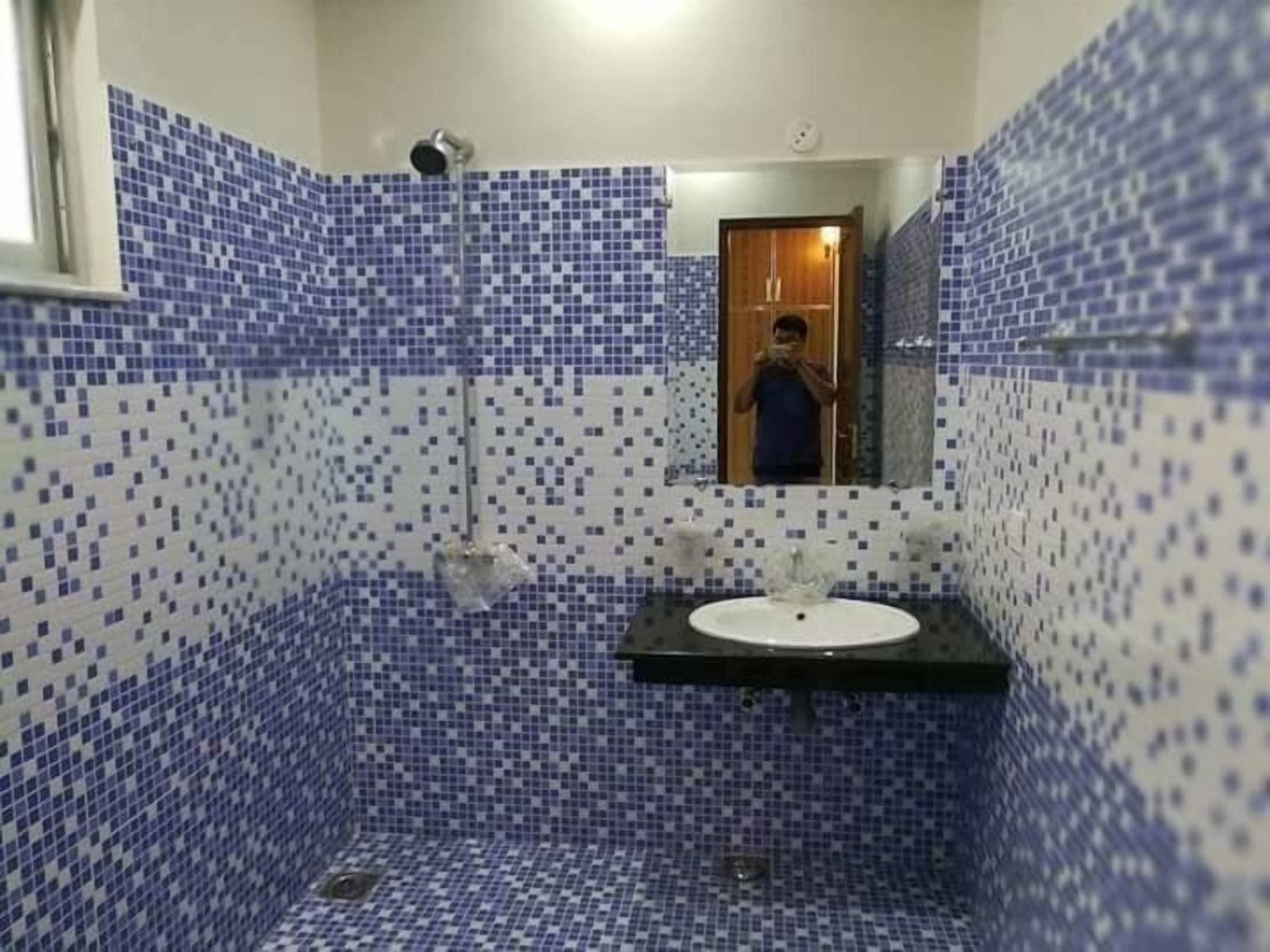 Une salle de bain avec un sol et des murs carrelés, un lavabo et une douche.