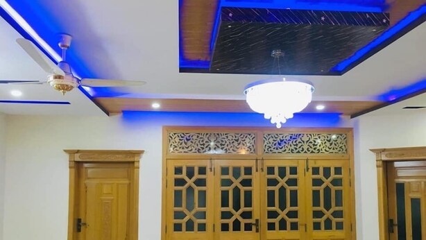 A room with a ceiling fan, a chandelier, and a set of wooden doors with intricate designs.
