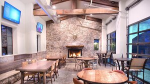 A rustic interior with stone walls, wooden tables, and chairs, featuring a fireplace and large windows. - Miles of walking, hiking or biking trails! (Hunt)