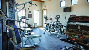 A gym with various exercise machines, including treadmills and weight machines, and a digital display showing workout metrics. - Miles of walking, hiking or biking trails! (Hunt)