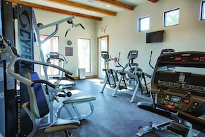 A gym with various exercise machines, including treadmills and weight machines, and a digital display showing workout metrics. - Miles of walking, hiking or biking trails! (Hunt)