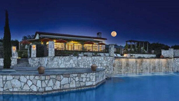 A stone-walled infinity pool with a view of a lit-up building and a full moon in the sky. - Miles of walking, hiking or biking trails! (Hunt)