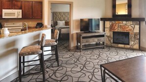 A compact living space with a kitchenette, a flat-screen TV, a stone fireplace, and a patterned carpet. - Miles of walking, hiking or biking trails! (Hunt)