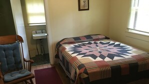 Una habitación pequeña y acogedora con cama, una silla, un lavamanos y una ventana.