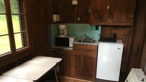 Una cocina compacta con armarios de madera, un refrigerador blanco, un microondas y una cafetera.