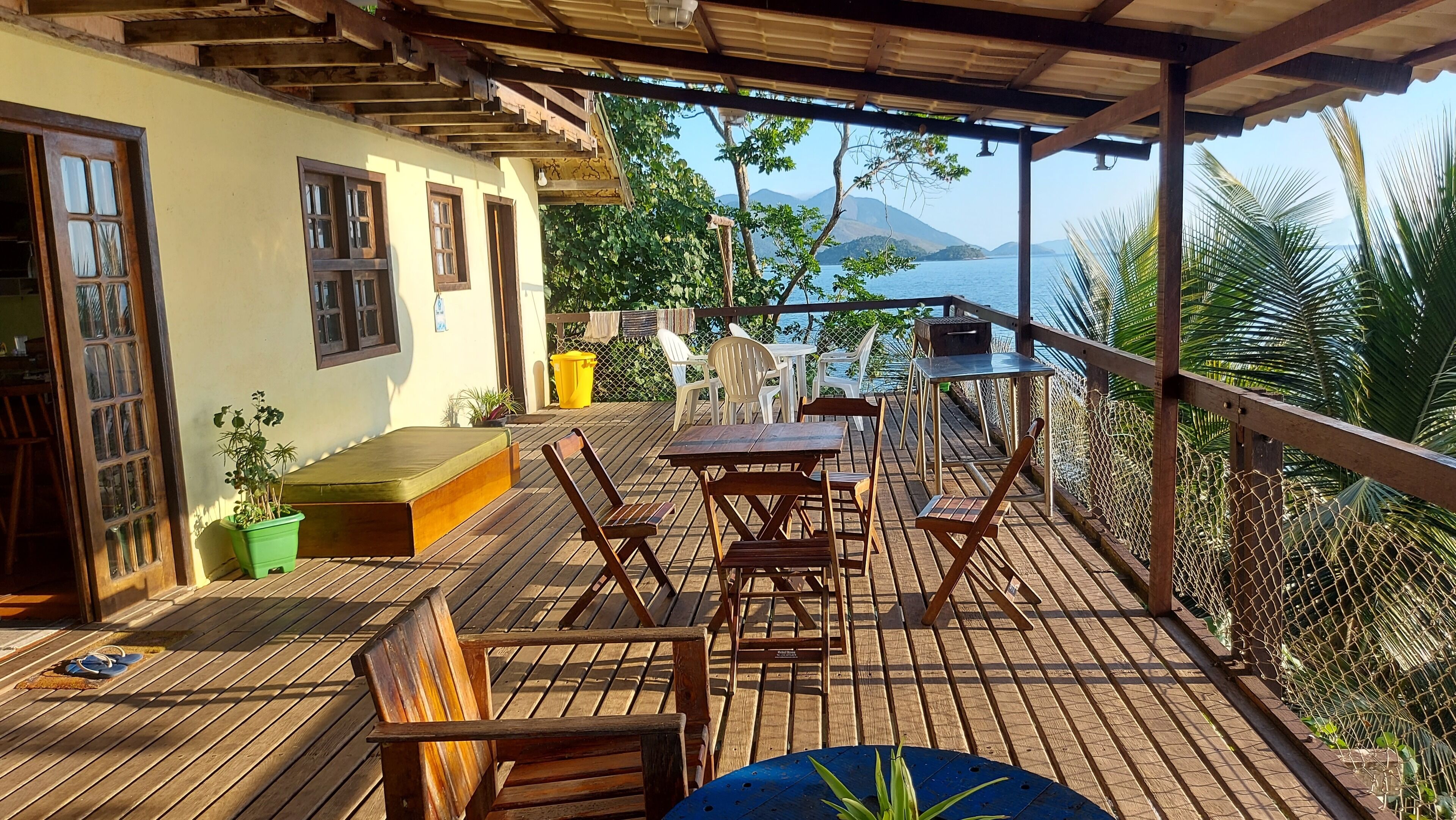 A wooden deck with outdoor seating, a view of the sea, and a covered area with a pergola.