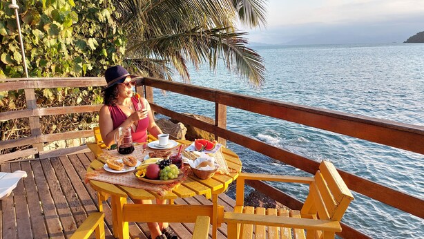 A wooden deck with a table set for a meal, overlooking a body of water.
