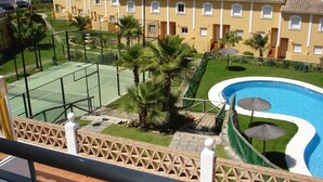 A hotel courtyard with a tennis court, swimming pool, and palm trees. - Dream vacation in Islantilla (Lepe)