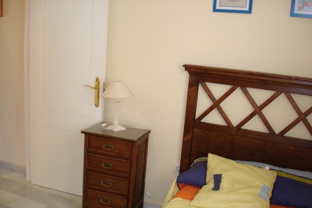Ein Schlafzimmer mit einem hölzernen Bett, einem Nachttisch mit Lampe und einer Wand mit gerahmten Bildern.