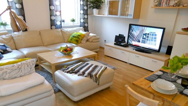 En moderne stue med sofa, sofabord, skammel og fjernsyn på et skab.