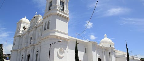 Una iglesia blanca de grandes dimensiones con una torre de campanas y una cúpula, que presenta una entrada imponente y escaleras que conducen a ella.