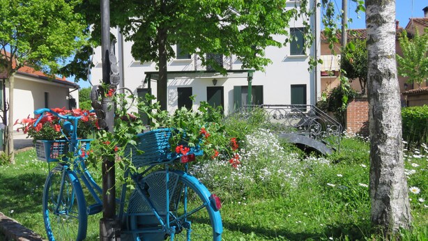A blue bicycle with baskets, parked in a lush garden with a building in the background. - 2 bedroom apartment, Mira, Venice, with swimming pool (Oriago)
