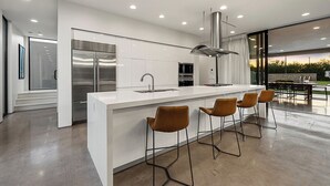 Eine moderne Küche mit einer großen Kochinsel, Edelstahlgeräten und einer Bar mit Hockern.