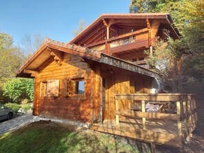 Eine Holzhütte mit Balkon, Veranda und kleiner Terrasse.