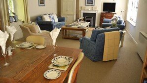 Un salón con una mesa de comedor lista para una comida, una chimenea y un televisor al fondo.