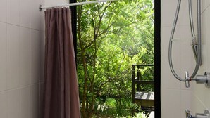 A shower area with a view of a lush green garden.