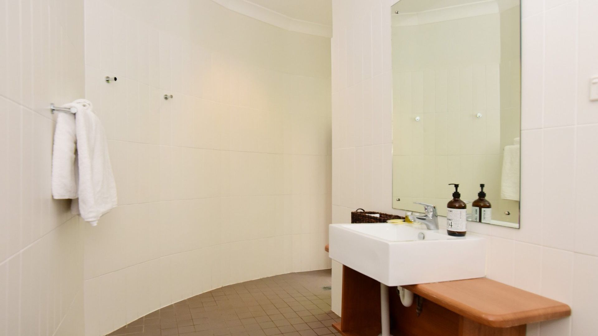 A modern bathroom with a white sink, mirror, and white tiles.