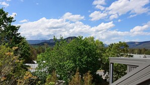 A view of a mountainous landscape with a clear sky and scattered clouds.