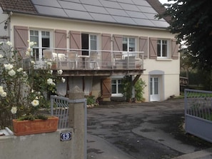 Un edificio de dos pisos con un balcón y un pequeño jardín.