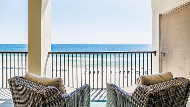 Ein Balkon mit Korbstühlen und Blick auf den Strand.