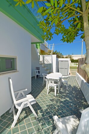 A patio with a table and chairs, a staircase, and a view of the sky.