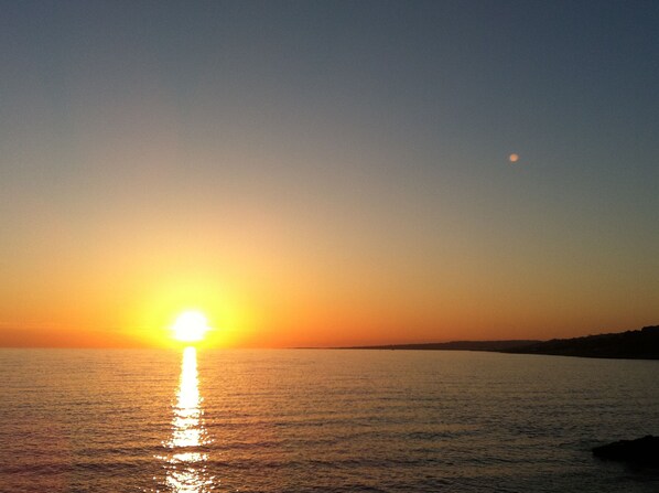 A sunset over a calm body of water with a clear sky.