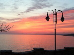 A sunset over a body of water with a street lamp in the foreground.