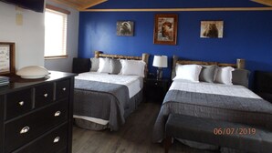 Un dormitorio con dos camas, un aparador y un ventilador de techo.