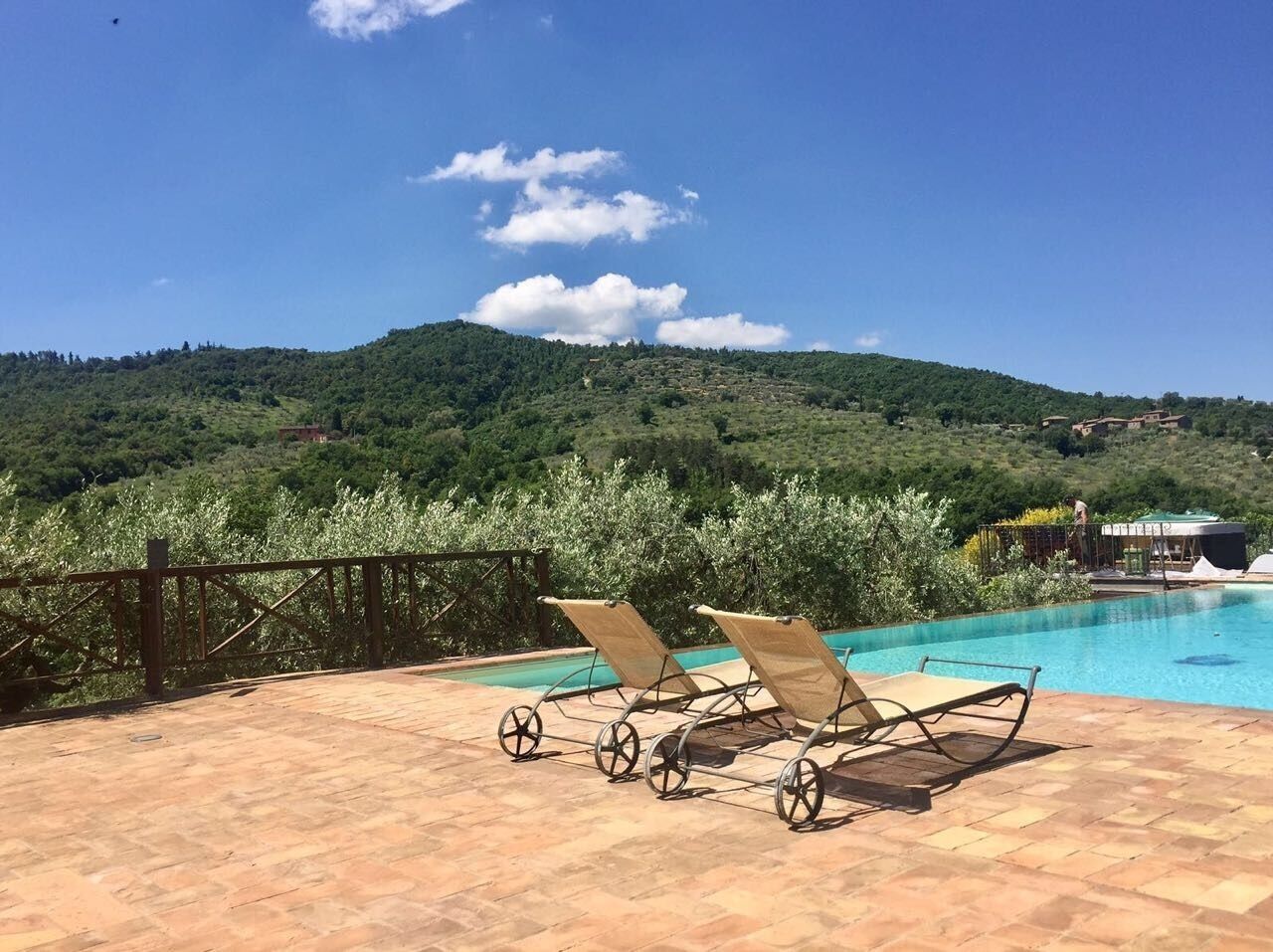 A pool area with lounge chairs and a view of a green hillside.