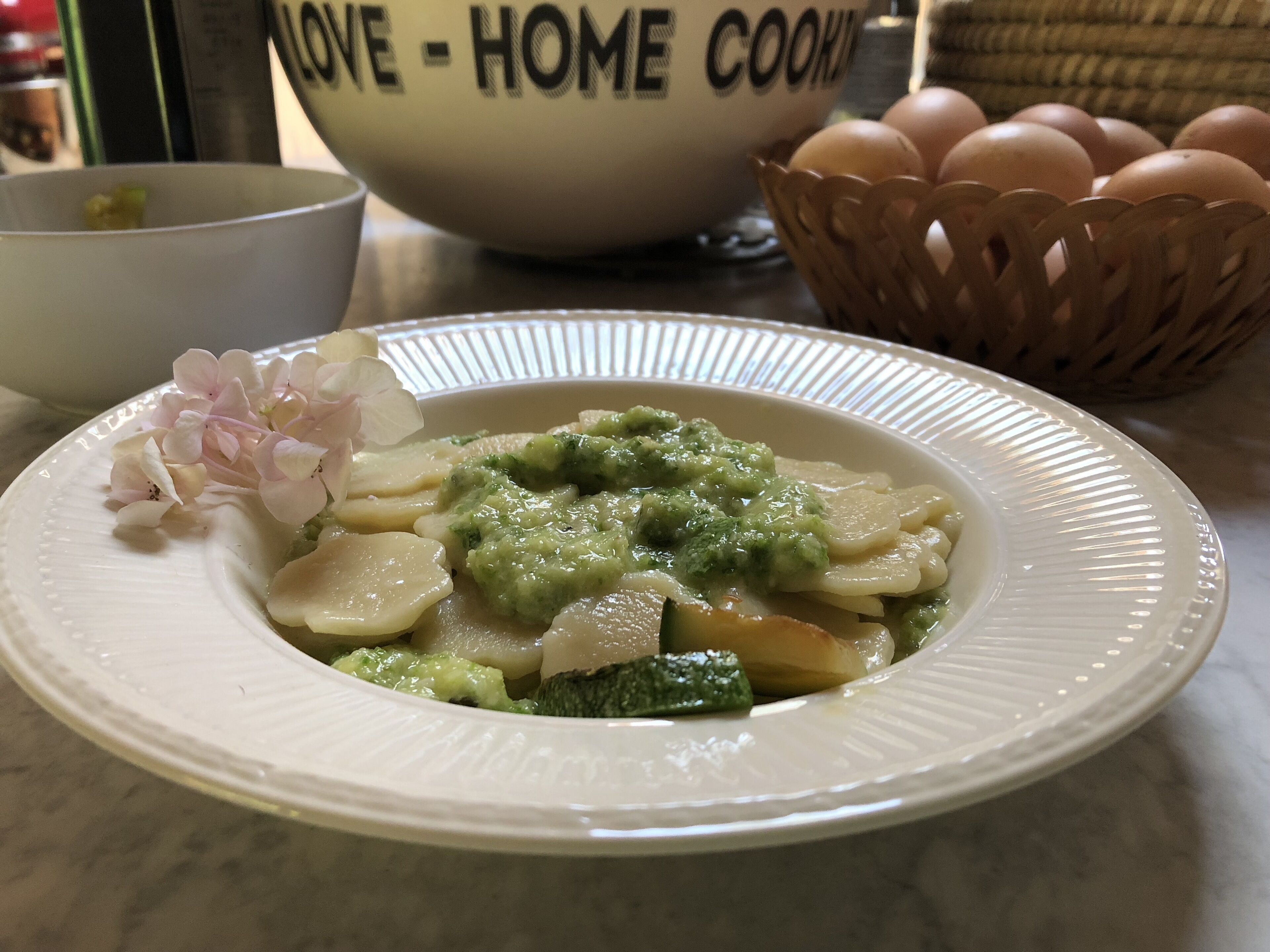 Ein Teller Essen mit grüner Soße, einer weißen Schüssel und einem Korb Eier.