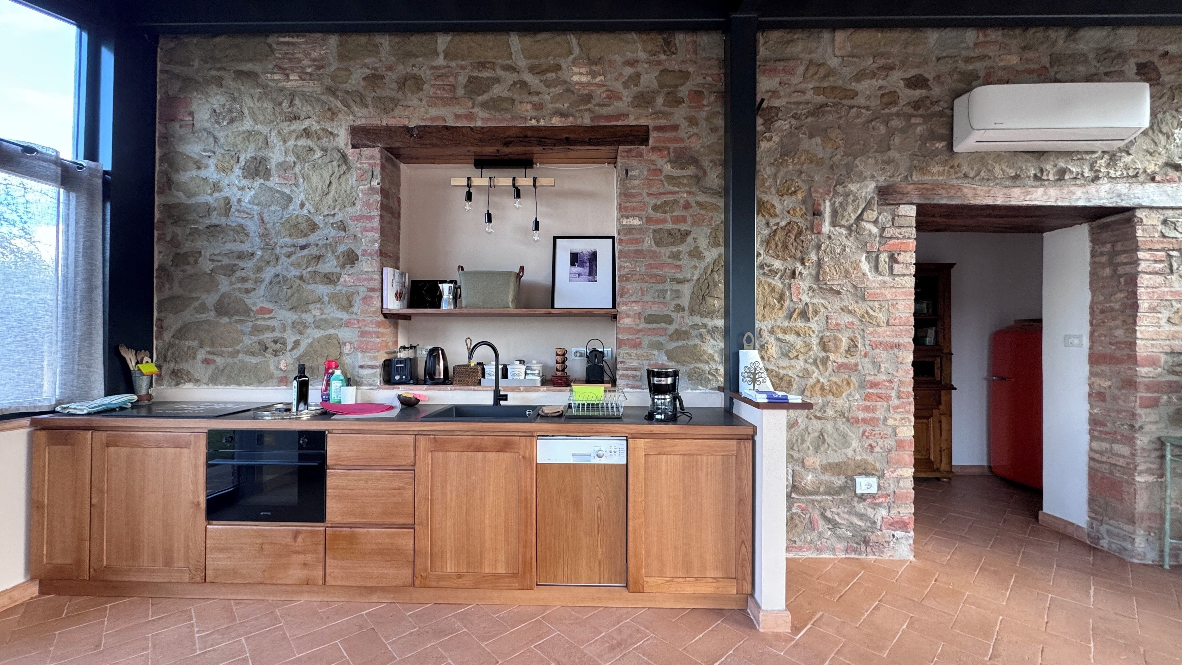 Una cucina con parete in pietra, mobili in legno e forno incassato.