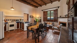 A kitchen with wooden cabinets, a dining table, and a fireplace. - Central Antigua apartment with kitchen (Antigua Guatemala)
