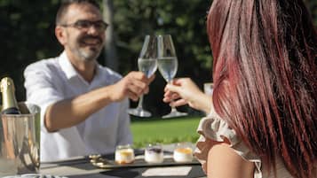 A dining table with a bottle of champagne, two glasses, and three small desserts.