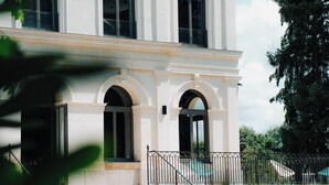 A two-story building with a symmetrical facade, large windows, and a central entrance with a staircase leading to the ground floor. - Hôtel Le Corbusson Laval Ouest (Saint-Berthevin)
