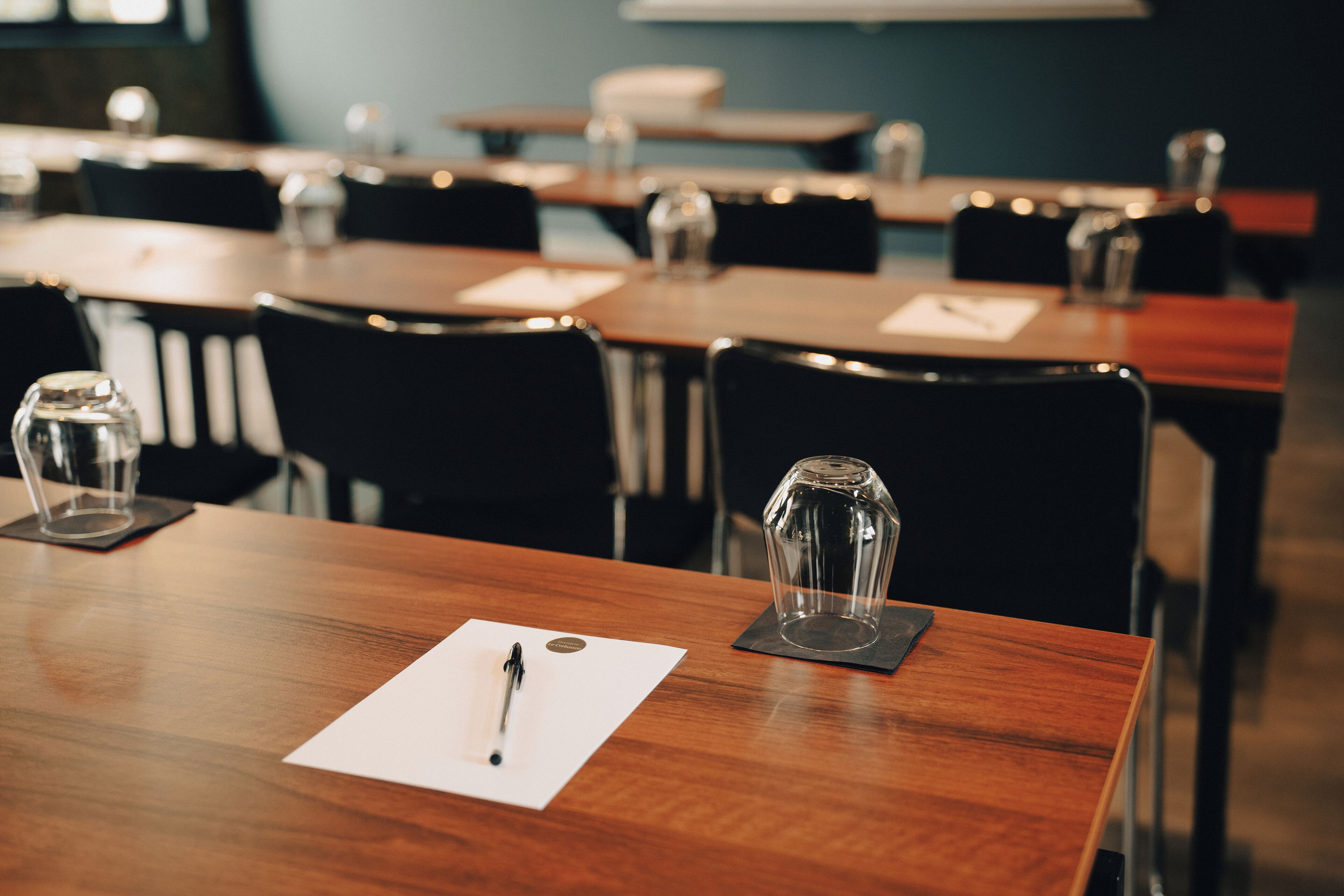 A conference room with wooden tables and black chairs.