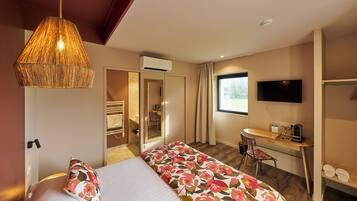 A hotel room with a bed, a desk, a chair, a television, and a window.
