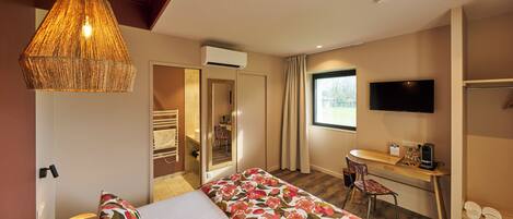 Una habitación de hotel con cama, escritorio, silla, televisor y ventana.